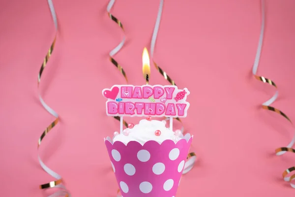 Kızlar ya da kadınlar için doğum günü pastası ya da pembe arka planda yanan mumu olan bir kek. Kutlama konsepti, pembe bir yıldönümü.