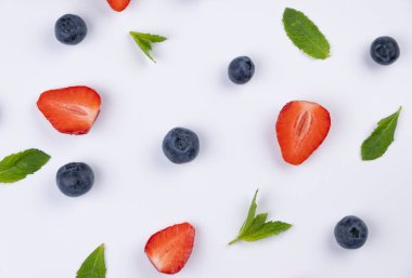 Beyaz arka planda yabanmersini, çilek ve nane yaprakları. Sağlıklı beslenme kavramı. Yaz aydınlığı arka plan, gıda tasarımı. 