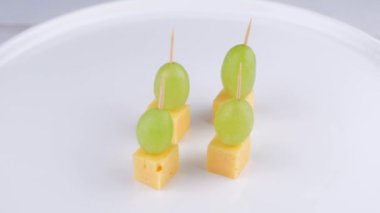 rotating cheese and grape canapes on white plate or background closeup,snack concept. High quality 4k footage