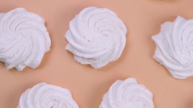 Rotating background of marshmallows or cakes, birthday cakes on a beige background. The concept of celebrating a party, anniversary in pink colors. High quality 4k footage