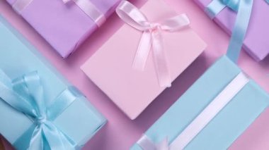 Renkli hediye kutularıyla donatılmış pembe arka planda pastel renkli kurdeleler ve fiyonklar, doğum günü tatili konsepti, satışlar. Yüksek kalite 4k görüntü