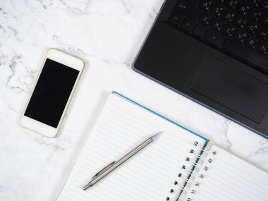 Mermer masadaki dizüstü bilgisayar akıllı telefonu ve gümüş kalem. Üst görünüm boşluğu kopyala