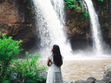 Beyaz elbiseli kadın ulusal parktaki güzel şelalede duruyor taze doğa, doğadaki seyahat konsepti kızı