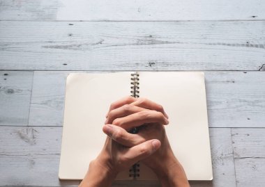 Dua eden eller boş sayfada ve güneş ışığı doğanın gölgesi beyaz ahşap arka plan görüşünde, Tanrı 'ya dua et kavramı