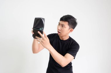 Siyah gömlekli genç adam cüzdanında para buluyor. Yüzü ciddi bir şekilde soyutlanmış, zavallı adam konseptinde.