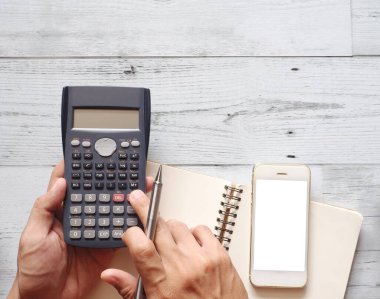 Akıllı telefon ve beyaz ahşap arka plan üst görünüm uzay iş konsepti boş sayfa defteri ile hesaplama için hesap makinesi kullanarak gümüş kalemle el