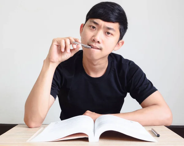 Young man with pen think and serious face with the book on the desk look at camera on white isolated,Study book concept