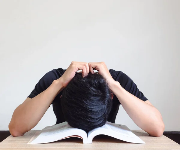 Man close his head on open book and touch head by hand on the desk feel