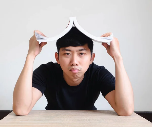 Young man bored and disheartened close the book on his head on white isolated,Study and homework concept
