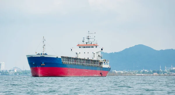 Cargo ship in the ocean with the island and mountain background,Transport ship on the sea front of dock and isle with the blue sky