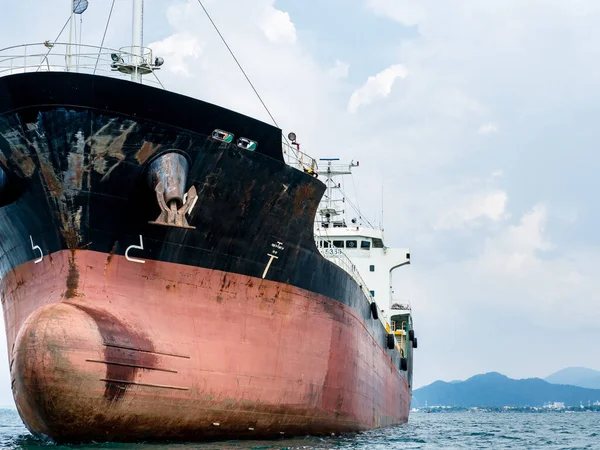 Large logistic ship in the ocean with view mountain on island background and cloudy on sky,Big Shipping boat transportation concept on the sea