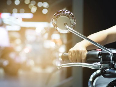 Motosiklet arka planında erkek eli bulanık, el tutma kolu hafif ışıklı motorsiklet çubuğu