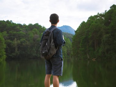 Göl ve vadi arka planında duran genç adam, doğal olarak, gezgin adam dağa ve göle bakıyor.