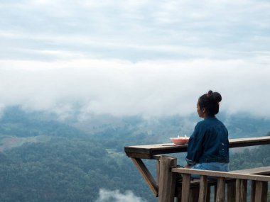 Kadın, odun çubuğunda oturuyor dağların arasında doğal ve sisli vadide
