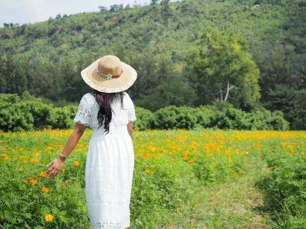 Asian woman traveler walking in flower park and mountain view background,Yong woman white dress travel in flower park