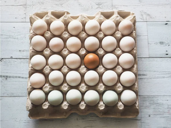 Egg in duck eggs group in carton box on white wood table difference concept idea and nature light and shadow top view