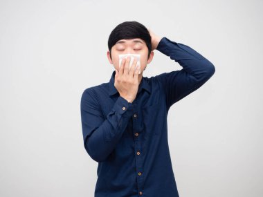 Hasta bir adam hasta ve başı ağrıyor. Beyaz arka planda kağıt mendil tutuyor.