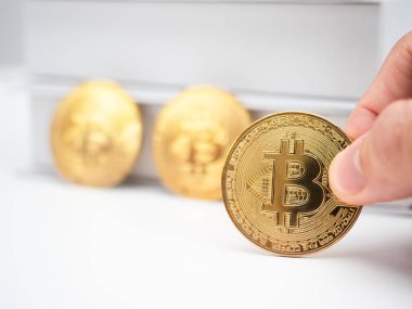 Yakın plan parmak altın Bitcoin 'i arka planda tutuyor.