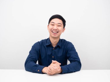 Genç adam oturuyor ve mutlu gülüyor.