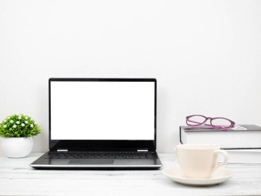 Laptop kahve fincanı ve gözlüklü çalışma odasının olduğu masada.