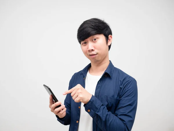 Young man point finger at mobile phone in his hand feeling confused white background