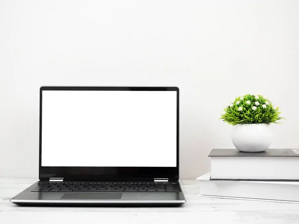 Laptop on the desk with book and vase workspace at home