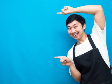 Önlük takan Asyalı adam işaret parmağı ile mavi arkaplanı kopyaladı