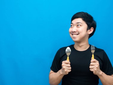 Elinde çatal bıçak takımı olan Asyalı bir adam yiyeceği düşünüyor ve fotokopi odasına bakıyor.