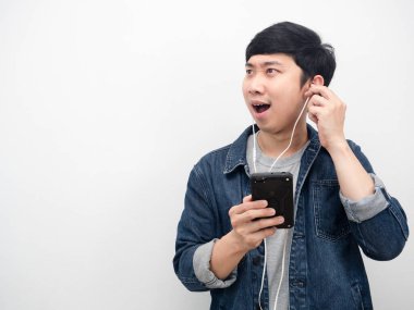 Asyalı erkek kot gömleği kulaklık kullanıyor. Heyecan verici duygu fotokopi alanına bakıyor.