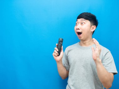 Asyalı adam uzaktan kumandalı televizyon tutuyor.