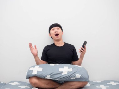 Cep telefonu alışverişini yapan adam yatakta şaşkın şaşkın yukarı bakıyor.