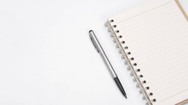 Masa üstü görünümü kopyalama boşluğunda gümüş kalem ve defter boş sayfası