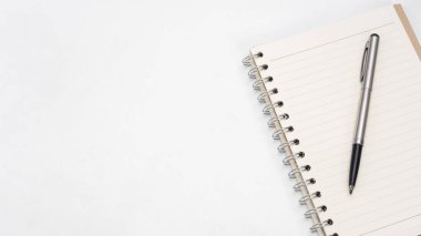 Masa üstü görünümü kopyalama boşluğunda gümüş kalem ve defter boş sayfası
