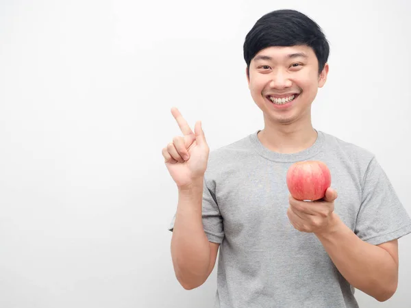 Asyalı adam kırmızı elma tutarak mutlu bir gülümseme ve fotokopi uzayı sağlık konseptine işaret ediyor.