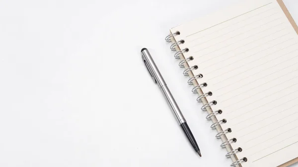 Masa üstü görünümü kopyalama boşluğunda gümüş kalem ve defter boş sayfası