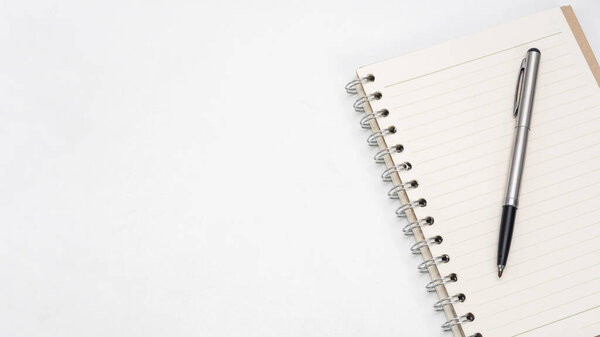 Silver pen and notebook blank page on the table top view copy space