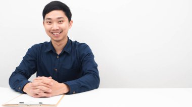 Masada oturan adam mutlu hissediyor ve gülümsüyor. Boşluğu beyaz arka planı kopyalayın.