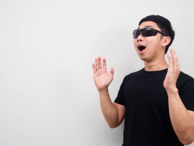 Güneş gözlüğü takan bir adam fotokopi çekilen beyaz arka plana bakarken şaşkına dönüyor.