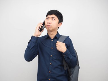 Sırt çantalı bir adam cep telefonuyla konuşuyor ve düşünceli.