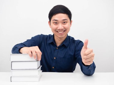 Masadaki kitaplarla gülümse ve başparmağını kaldır.