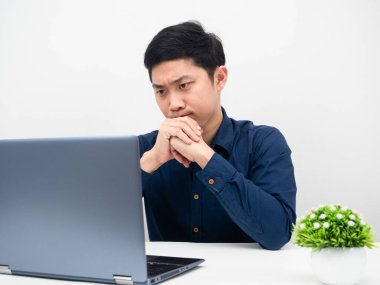 Asyalı adam masadaki dizüstü bilgisayarına bakıyor. Ciddi anlamda duygusal, beyaz arka plan.