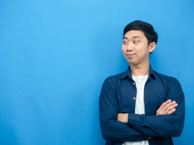 Cheerful man standing cross arm loking at copy space blue screen