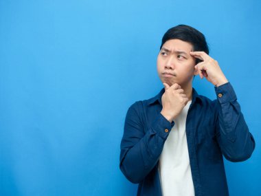 Asyalı adam jesti bir şeyin fotokopi uzayının mavi arka planına baktığını düşünüyor.