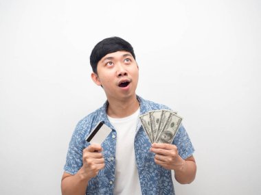 Elinde kredi kartı ve para olan adam mutlu bir şekilde gülüyor.