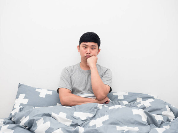 Asian man sit on the bed gesture bored looking at camera