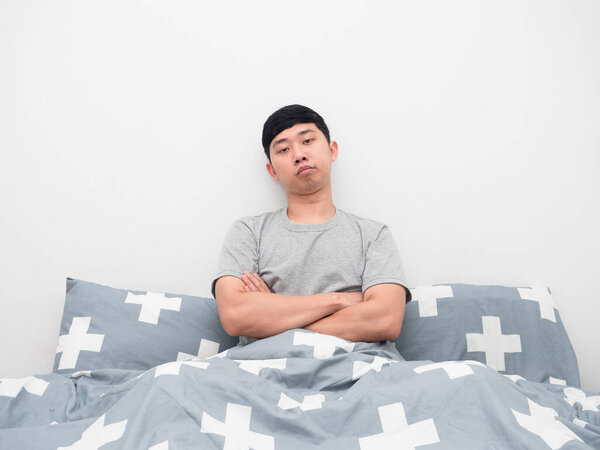 Man sitting on the bed gesture cross arm feeling bored