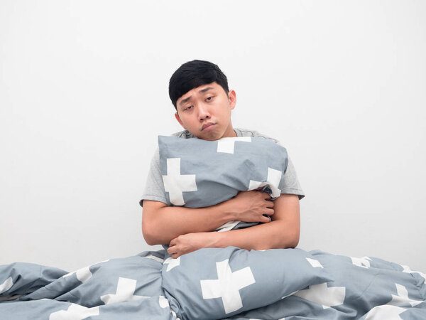 Man sitting on the bed hugging pillow feel sleepy and lazy