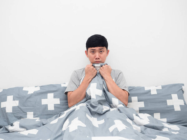 Man sitting on the bed cover blanket his body feeling afraid
