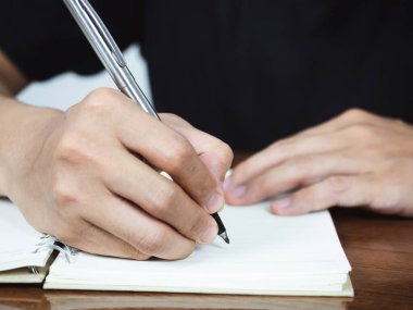Close up man hand writing pen on book page on table