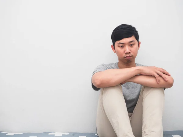 Young man sit on the bed hugging knee thoughtful sadness emotion white background